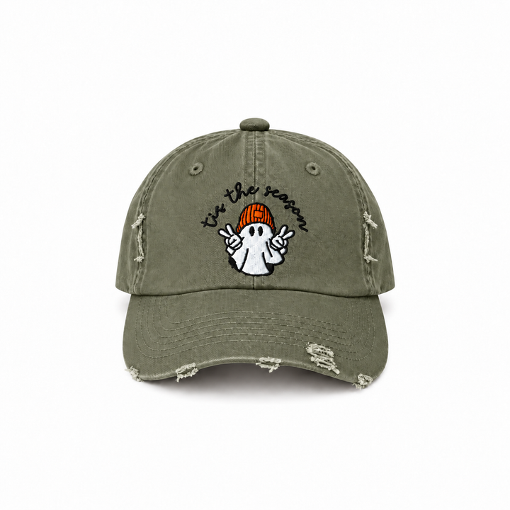 Light olive distressed cap with “’tis the season” lettering and a white ghost wearing an orange beanie.