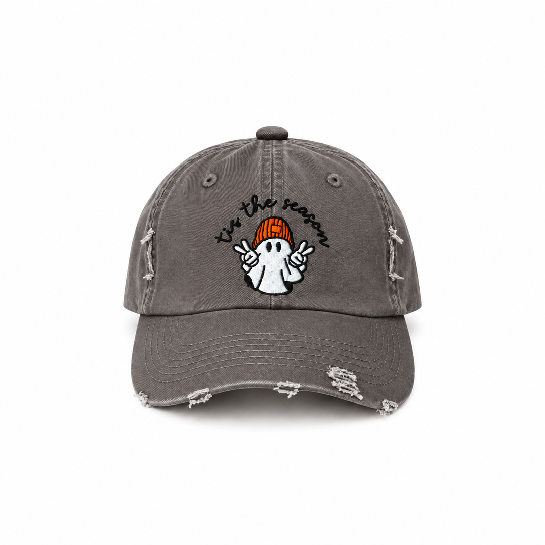 Nickel gray distressed baseball cap with “’tis the season” lettering and a white ghost wearing an orange beanie.