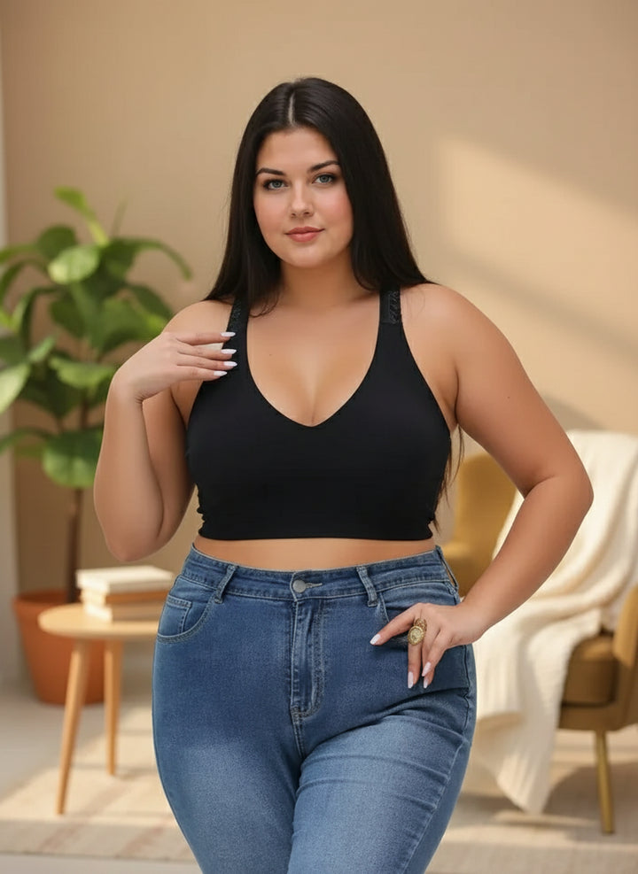 Woman wearing a black tank top and blue jeans against a plain background